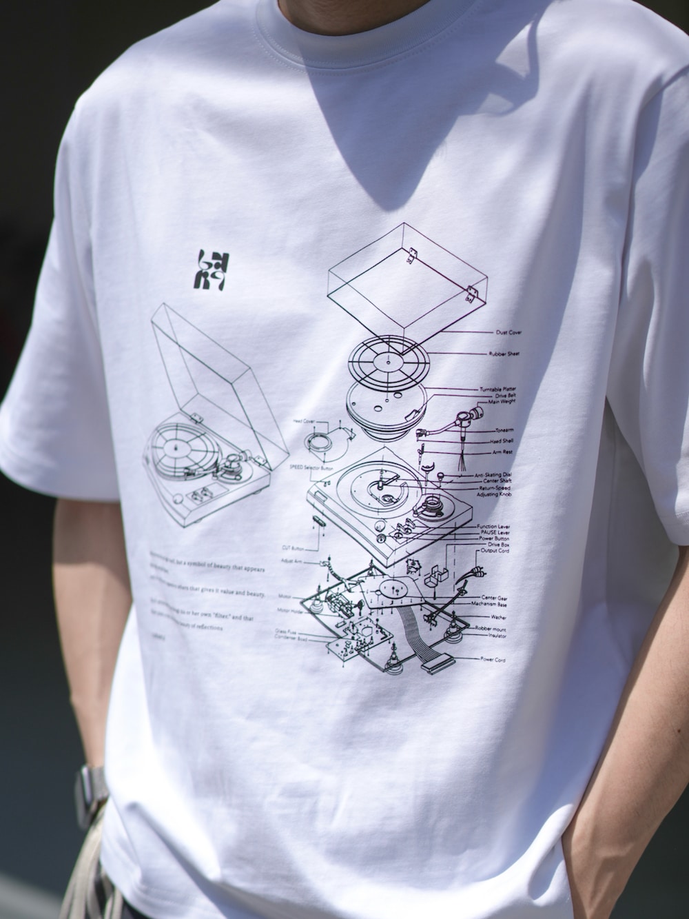 ホワイト系のTシャツ/カットソー、ブラック系のスラックス、ブラック系のエコバッグ/サブバッグを着用したメンズの春コーディネートの2枚目の写真