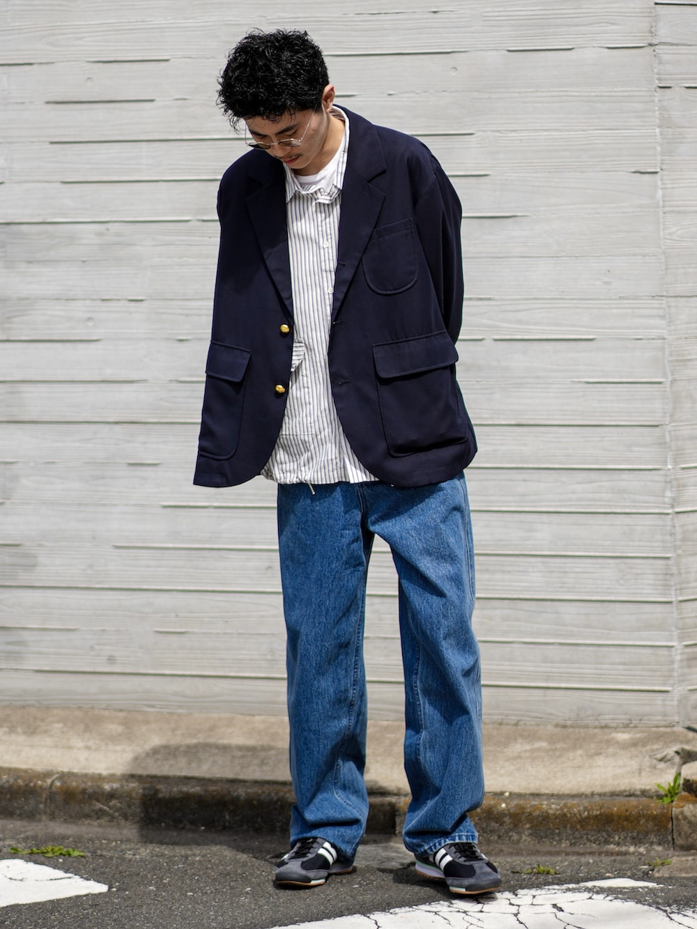 ブルー系のテーラードジャケット、ブルー系のデニムパンツ、ブラック系のスニーカーを着用したメンズの春コーディネートの3枚目の写真