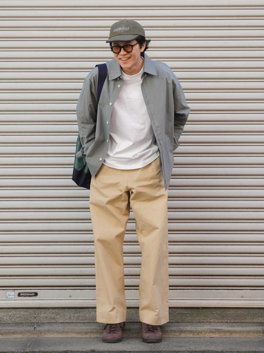 グリーン系のトートバッグ、ブルー系のシャツ/ブラウス、ベージュ系のチノパンツを着用したメンズの春コーディネートの2枚目の写真