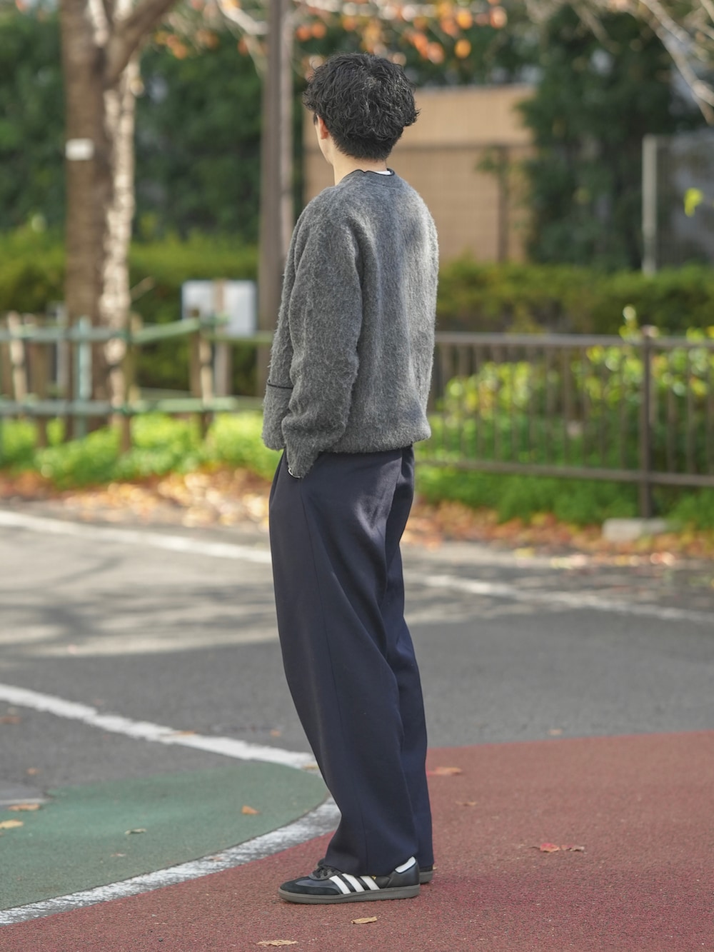 グレー系のニット/セーター、ブルー系のスラックス、ブラック系のスニーカーを着用したメンズの冬コーディネートの2枚目の写真