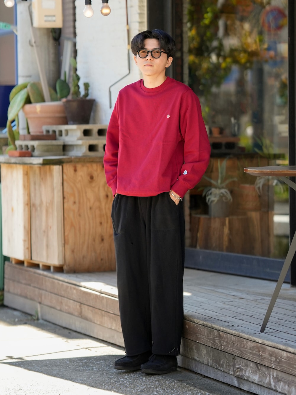 レッド系のスウェット、ブラック系のパンツ、ブラック系のモカシン/デッキシューズを着用したメンズの秋コーディネートの2枚目の写真