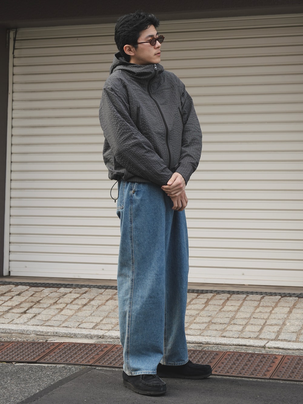 ブルー系のデニムパンツ、ブラック系のマウンテンパーカー、ブラック系のモカシン/デッキシューズを着用したメンズの冬コーディネートの2枚目の写真