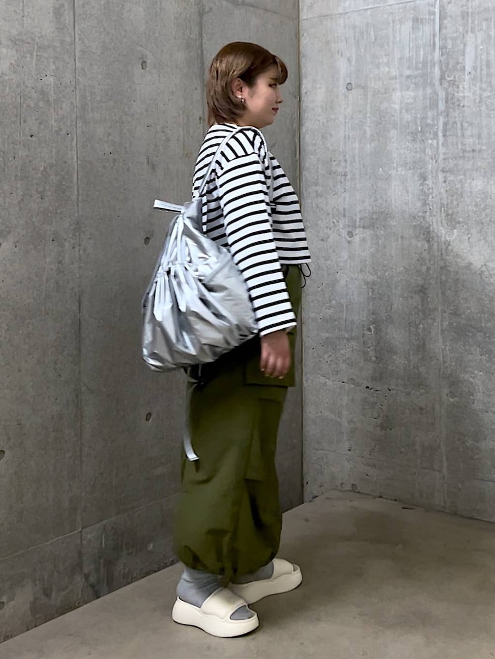 ホワイト系のサンダル、ブルー系のTシャツ/カットソー、シルバー系のバックパック/リュックを着用したレディースの春コーディネートの2枚目の写真