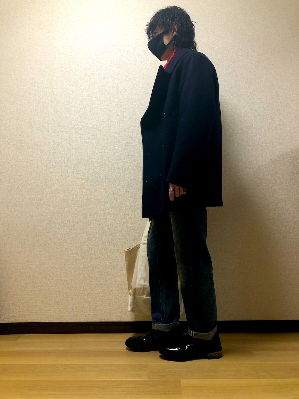 ホワイト系のトートバッグ、ブラック系のスニーカー、ブルー系のデニムパンツを着用したメンズの冬コーディネートの2枚目の写真