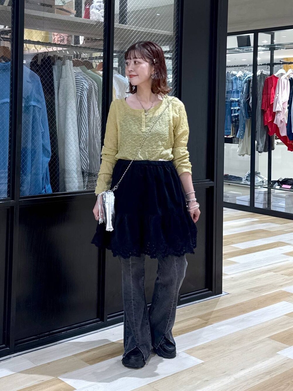 シルバー系のショルダーバッグ、グレー系のデニムパンツ、ブラック系のスニーカーを着用したレディースの夏コーディネートの2枚目の写真