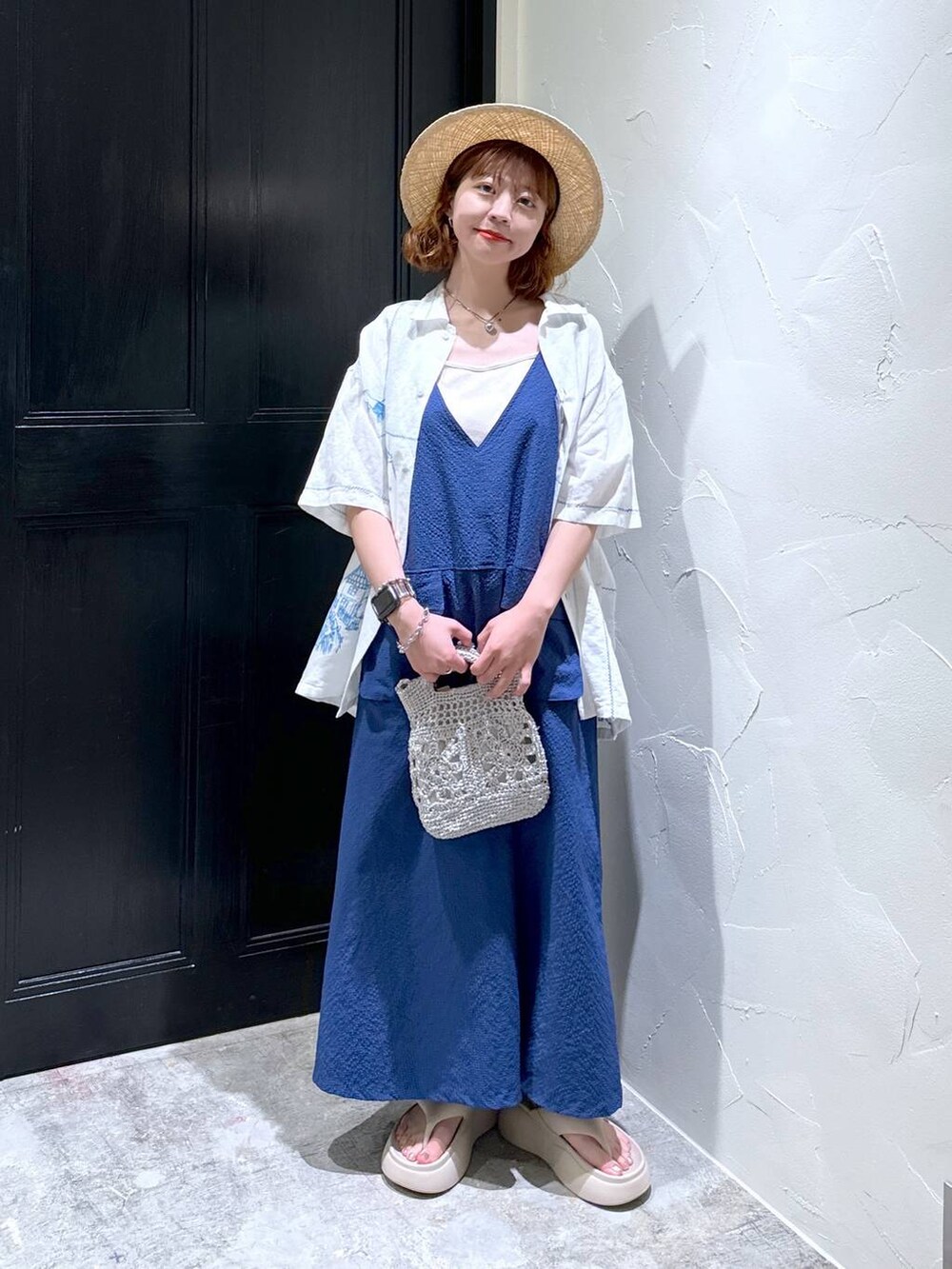 グレー系のショルダーバッグ、ベージュ系のサンダル、ブルー系のジャンパースカートを着用したレディースの夏コーディネートの2枚目の写真