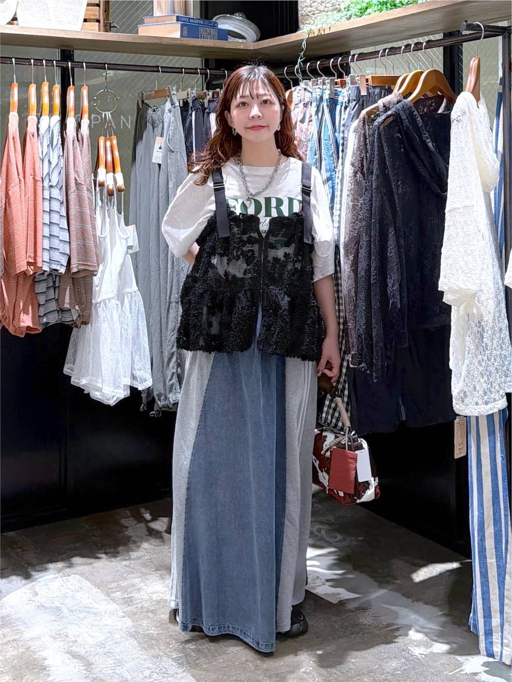 ブラック系のベスト、ベージュ系のTシャツ/カットソー、ブルー系のデニムスカートを着用したレディースの夏コーディネートの7枚目の写真