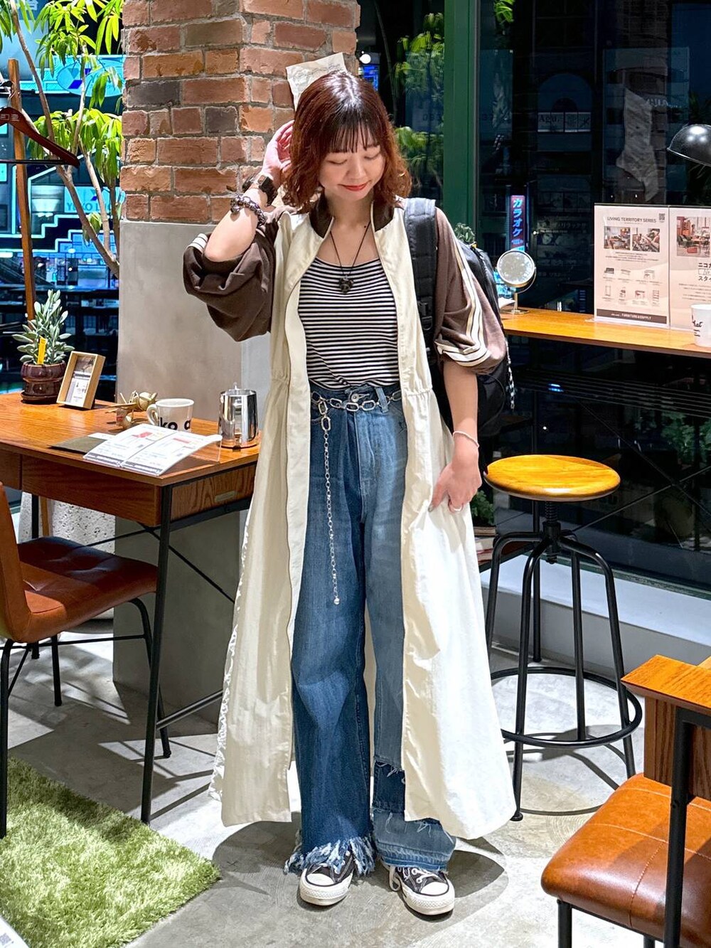 ブルー系のデニムパンツ、ベージュ系のワンピース、ホワイト系のキャミソールを着用したレディースの秋コーディネートの2枚目の写真