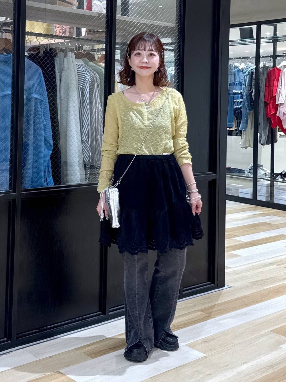 シルバー系のショルダーバッグ、グレー系のデニムパンツ、ブラック系のスニーカーを着用したレディースの夏コーディネートの3枚目の写真