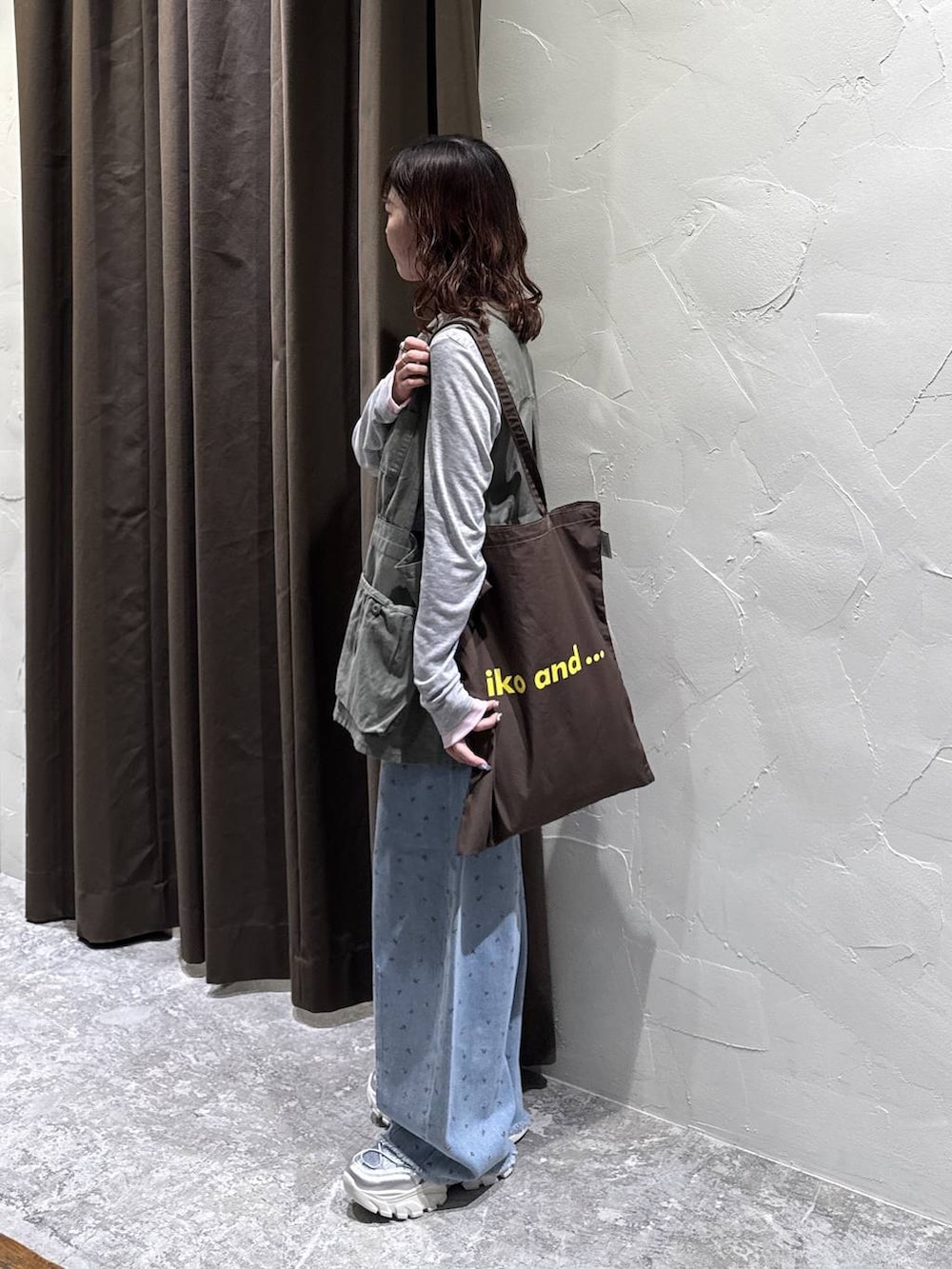 シルバー系のスニーカー、ブラウン系のトートバッグ、ブルー系のデニムパンツを着用したレディースの冬コーディネートの4枚目の写真