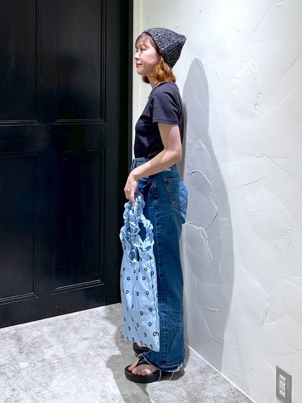 ブルー系のトートバッグ、ブラック系のサンダル、ブルー系のデニムパンツを着用したレディースの夏コーディネートの3枚目の写真