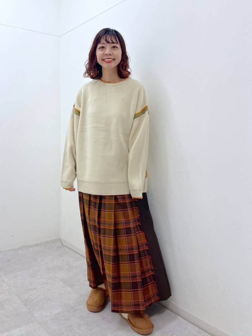 オレンジ系のスカート、ベージュ系のニット/セーター、イエロー系のその他シューズを着用したレディースの冬コーディネートの2枚目の写真