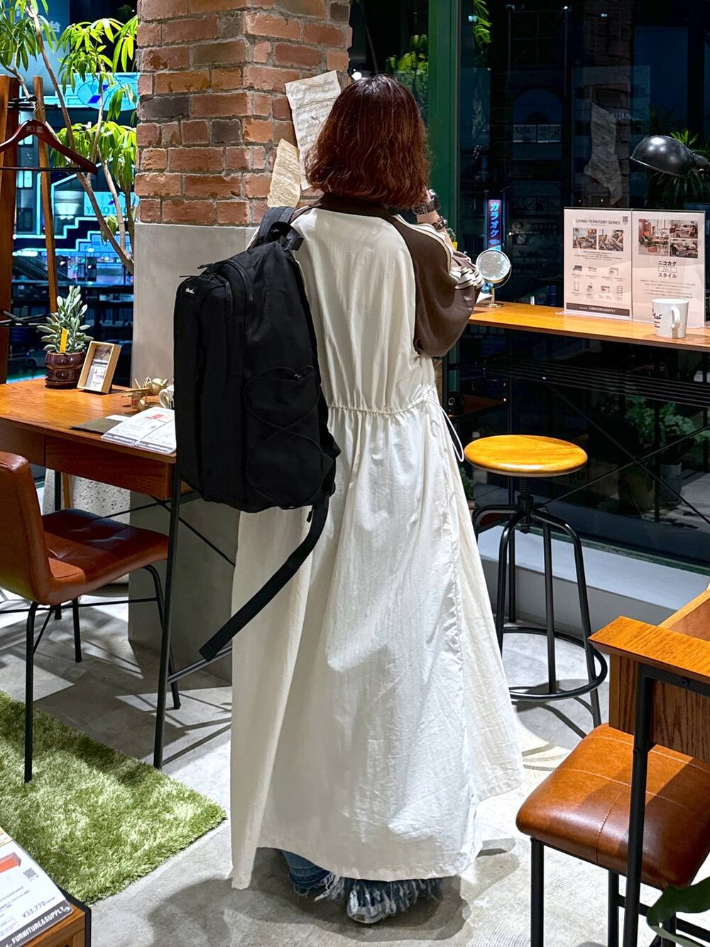 ブルー系のデニムパンツ、ベージュ系のワンピース、ホワイト系のキャミソールを着用したレディースの秋コーディネートの7枚目の写真