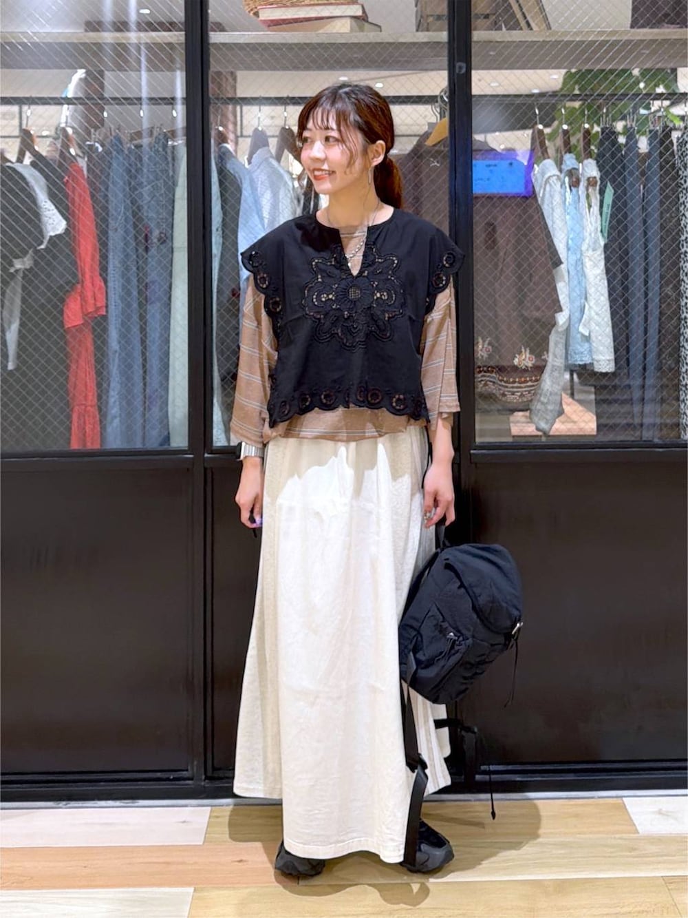 ブラック系のベスト、ブラウン系のTシャツ/カットソー、ブラック系のバックパック/リュックを着用したレディースの夏コーディネートの2枚目の写真