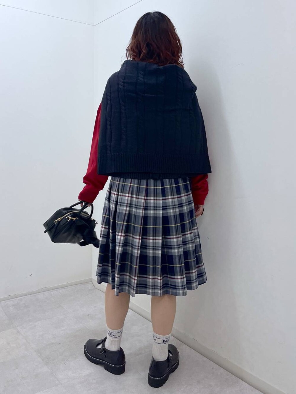 ブラック系のその他シューズ、ブラック系のショルダーバッグ、レッド系のTシャツ/カットソーを着用したレディースの冬コーディネートの6枚目の写真