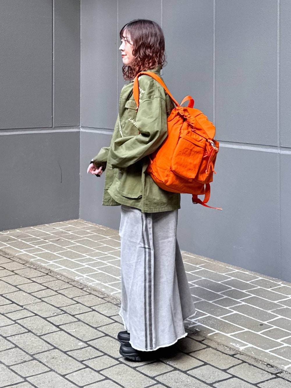 グリーン系のシャツ/ブラウス、オレンジ系のバックパック/リュック、ホワイト系のTシャツ/カットソーを着用したレディースの春コーディネートの3枚目の写真