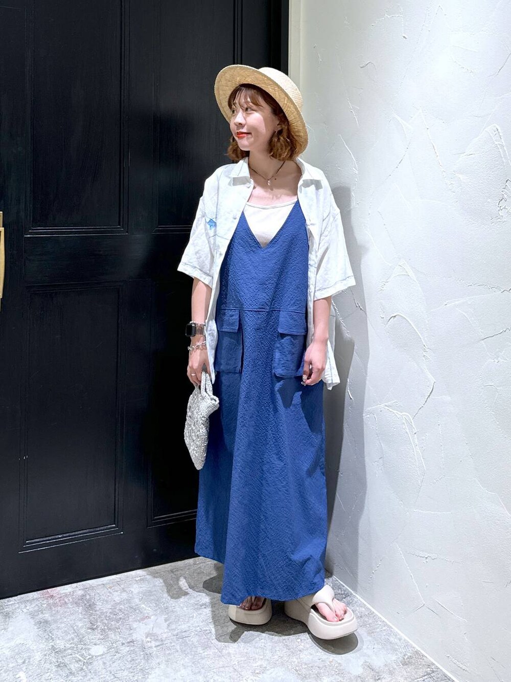 グレー系のショルダーバッグ、ベージュ系のサンダル、ブルー系のジャンパースカートを着用したレディースの夏コーディネートの4枚目の写真