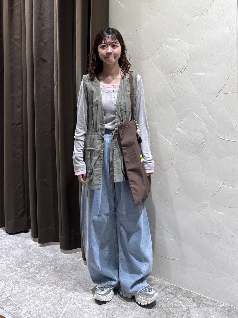 シルバー系のスニーカー、ブラウン系のトートバッグ、ブルー系のデニムパンツを着用したレディースの冬コーディネートの3枚目の写真