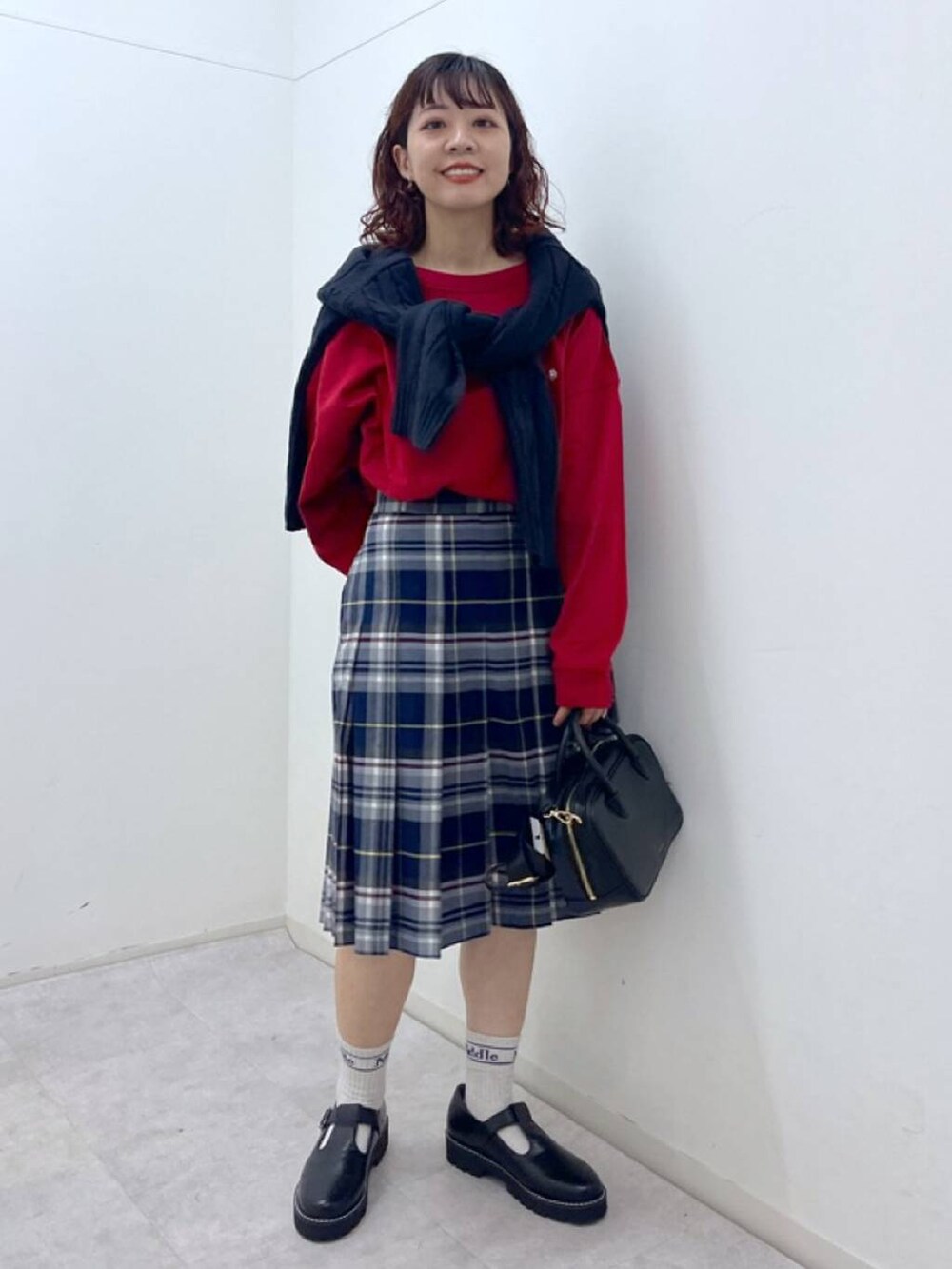 ブラック系のその他シューズ、ブラック系のショルダーバッグ、レッド系のTシャツ/カットソーを着用したレディースの冬コーディネートの3枚目の写真