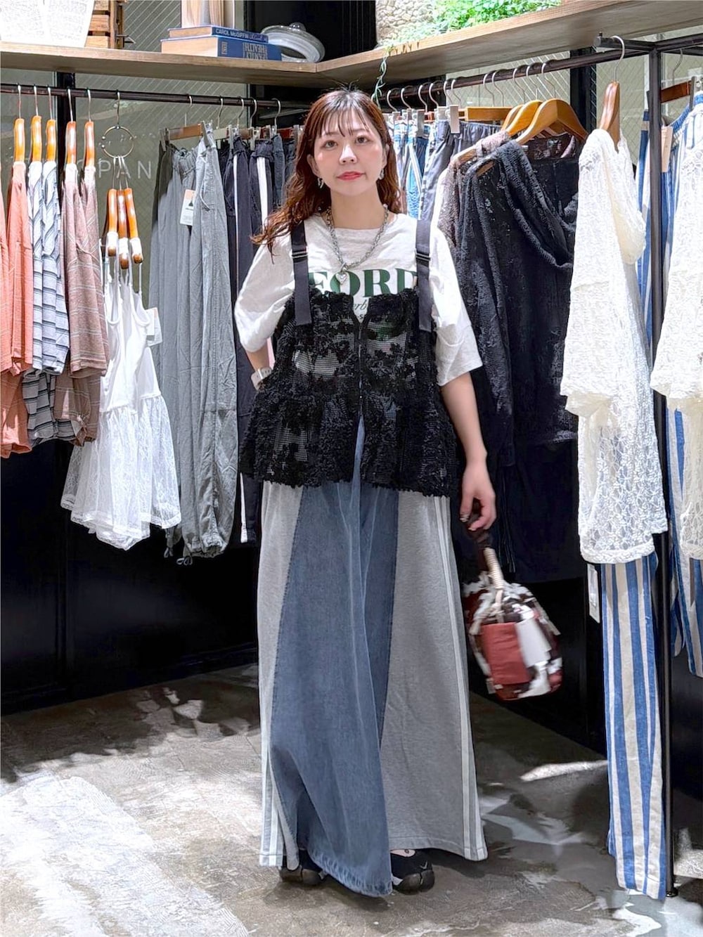ブラック系のベスト、ベージュ系のTシャツ/カットソー、ブルー系のデニムスカートを着用したレディースの夏コーディネートの2枚目の写真