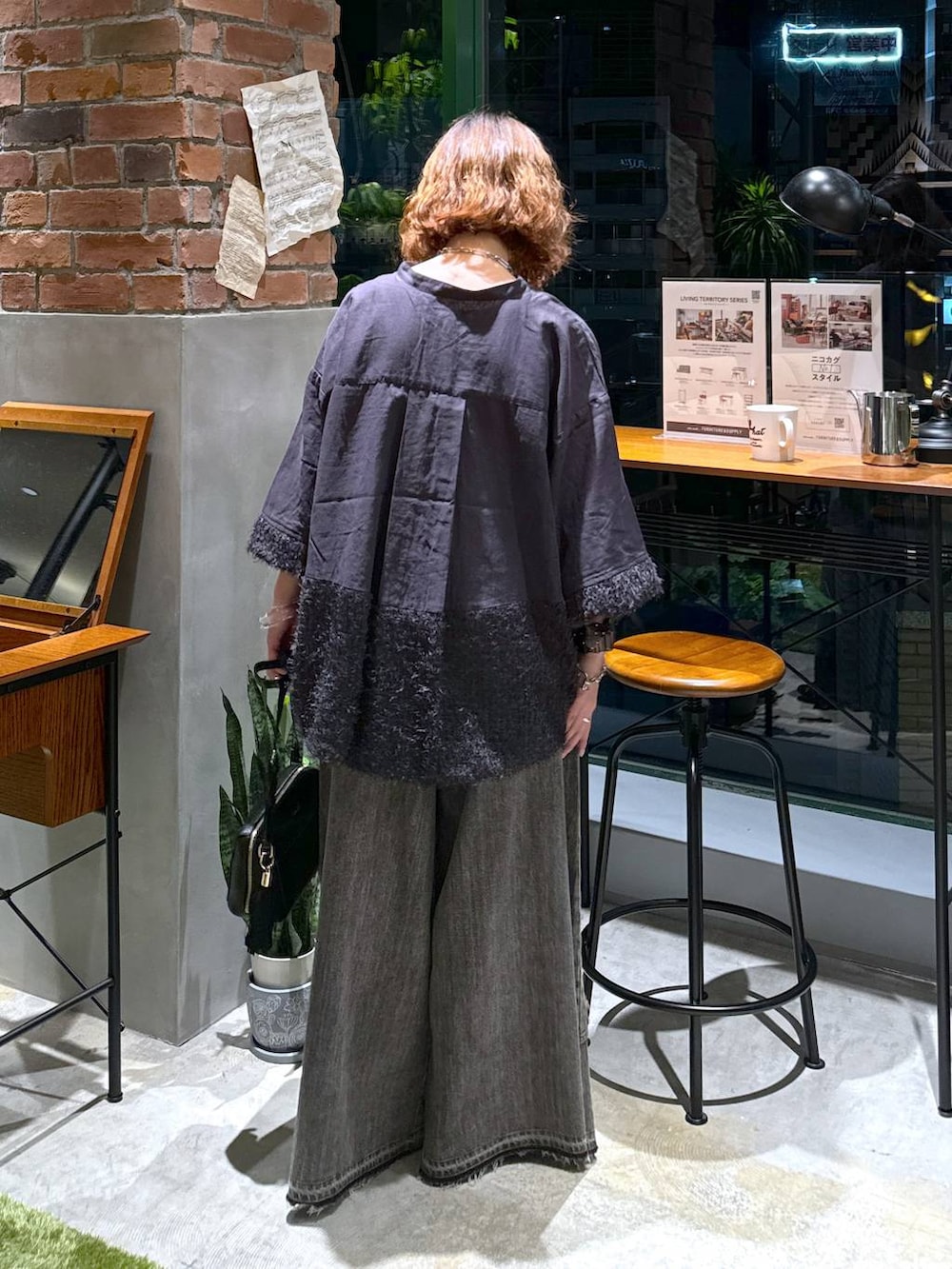 ブラック系のバレエシューズ、ブラック系のショルダーバッグ、ブラウン系のデニムパンツを着用したレディースの秋コーディネートの4枚目の写真