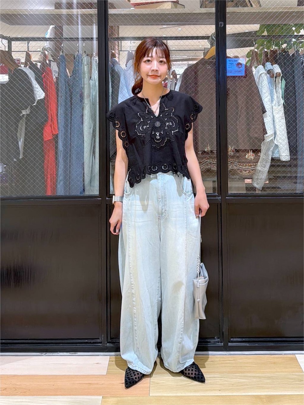 ブラック系のベスト、グリーン系のデニムパンツ、シルバー系のショルダーバッグを着用したレディースの夏コーディネートの2枚目の写真