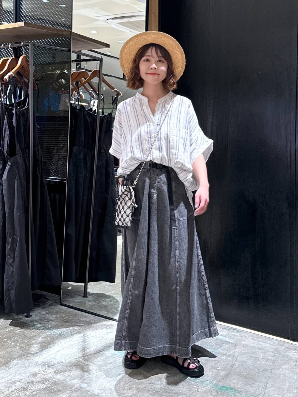 ブラック系のショルダーバッグ、ブラック系のサンダル、ベージュ系のシャツ/ブラウスを着用したレディースの夏コーディネートの2枚目の写真