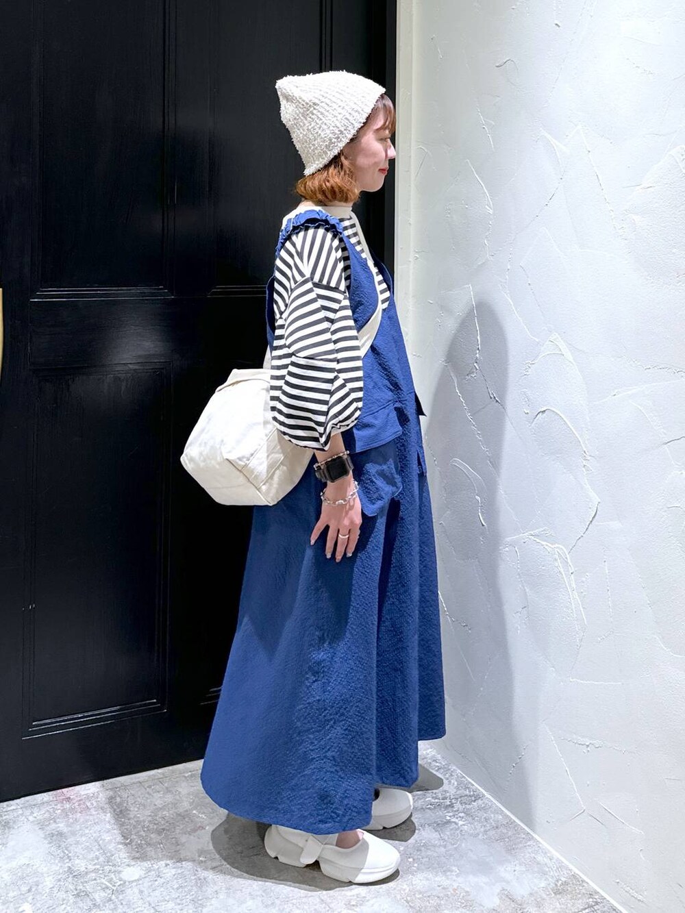 ブルー系のジャンパースカート、ベージュ系のスニーカー、ブラウン系のショルダーバッグを着用したレディースの夏コーディネートの5枚目の写真