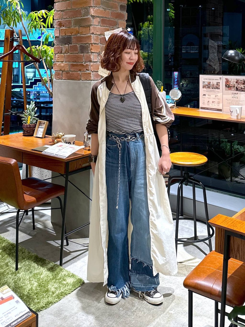 ブルー系のデニムパンツ、ベージュ系のワンピース、ホワイト系のキャミソールを着用したレディースの秋コーディネートの3枚目の写真