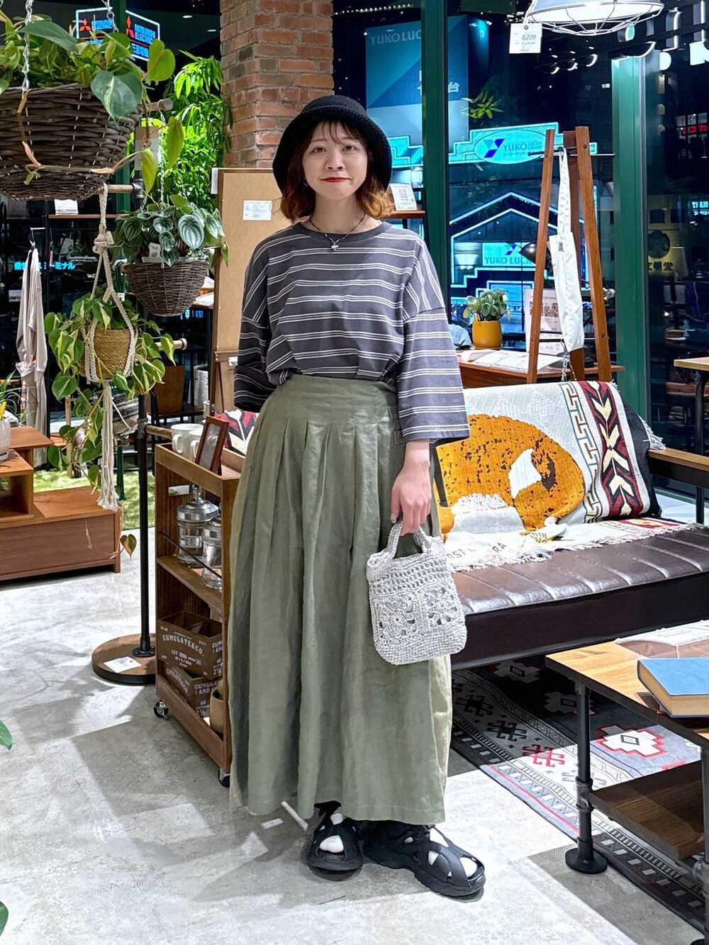 グレー系のショルダーバッグ、ブラック系のサンダル、グレー系のTシャツ/カットソーを着用したレディースの春コーディネートの2枚目の写真