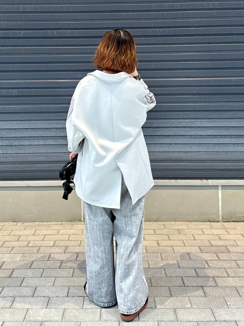 グレー系のデニムパンツ、グレー系のテーラードジャケット、ブラック系のスニーカーを着用したレディースの夏コーディネートの4枚目の写真