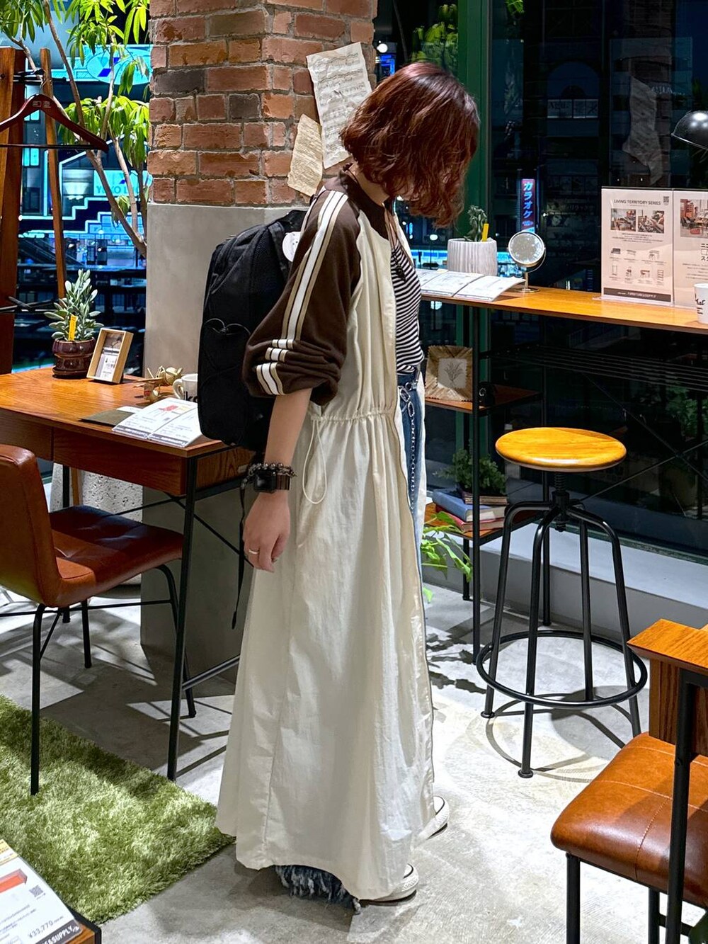 ブルー系のデニムパンツ、ベージュ系のワンピース、ホワイト系のキャミソールを着用したレディースの秋コーディネートの4枚目の写真