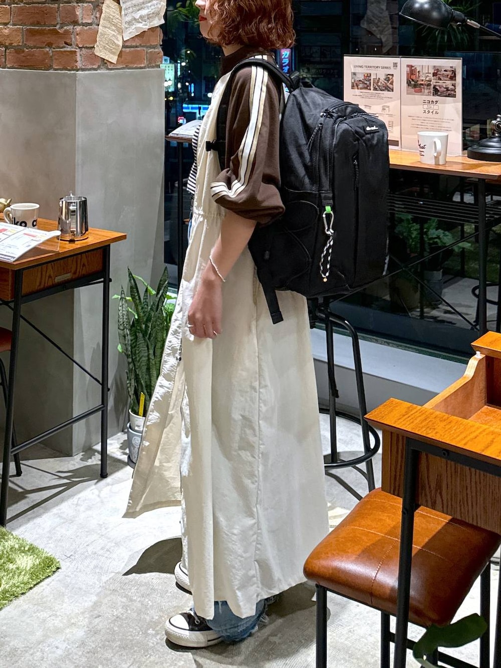 ブルー系のデニムパンツ、ベージュ系のワンピース、ホワイト系のキャミソールを着用したレディースの秋コーディネートの8枚目の写真