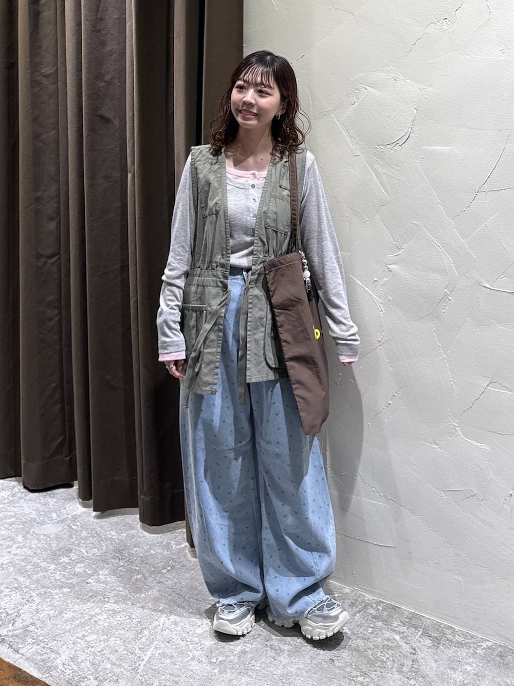 シルバー系のスニーカー、ブラウン系のトートバッグ、ブルー系のデニムパンツを着用したレディースの冬コーディネートの2枚目の写真