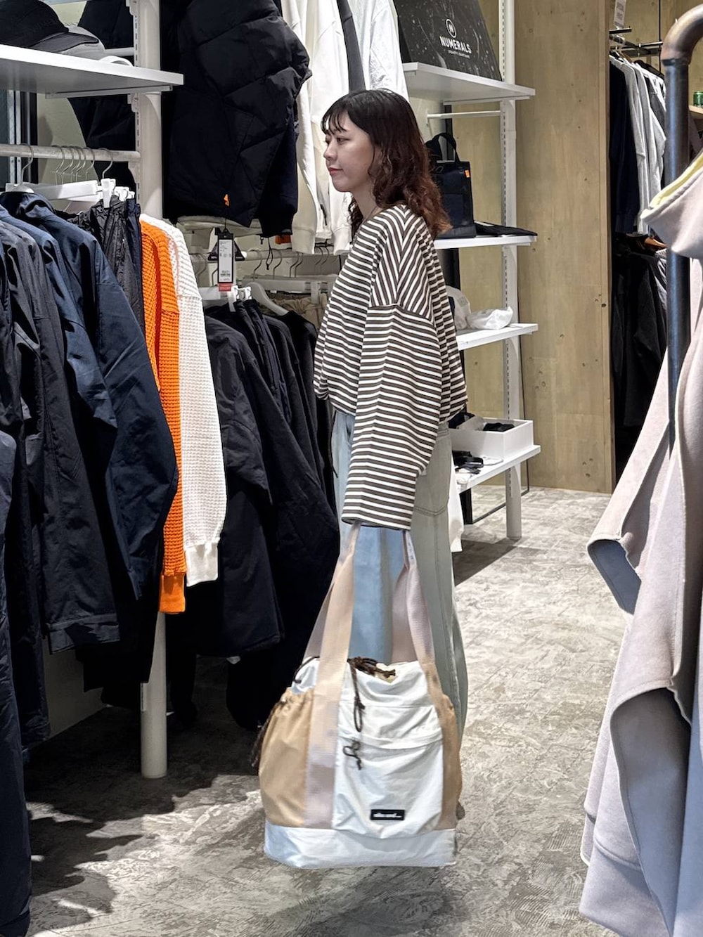 ブラック系のスニーカー、グリーン系のデニムパンツ、ベージュ系のトートバッグを着用したレディースの冬コーディネートの2枚目の写真