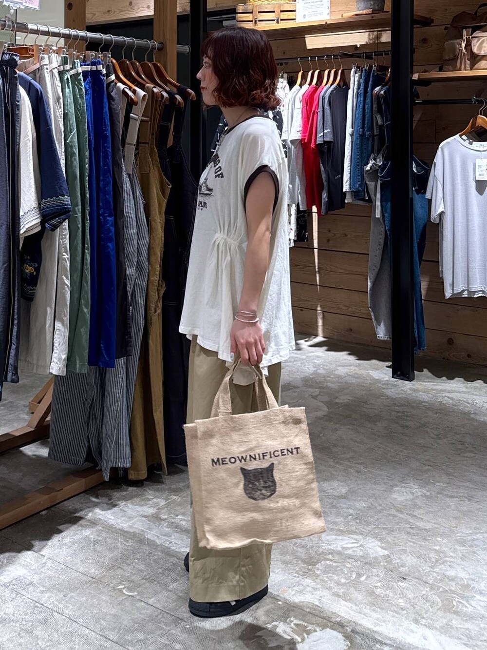 ベージュ系のチノパンツ、ホワイト系のTシャツ/カットソー、ブラック系のトートバッグを着用したレディースの夏コーディネートの2枚目の写真