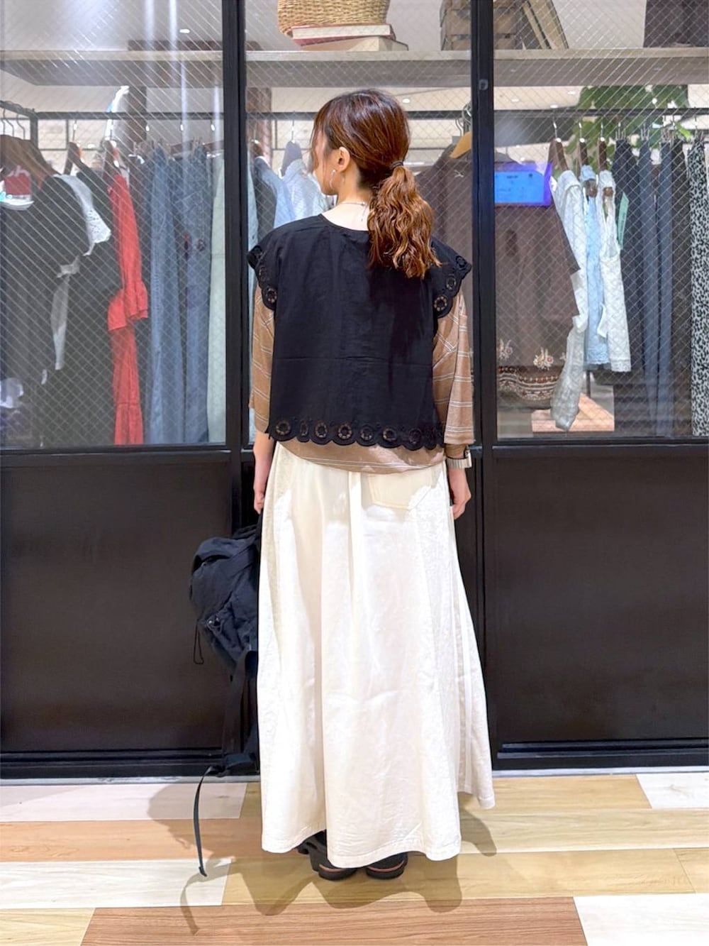 ブラック系のベスト、ブラウン系のTシャツ/カットソー、ブラック系のバックパック/リュックを着用したレディースの夏コーディネートの4枚目の写真