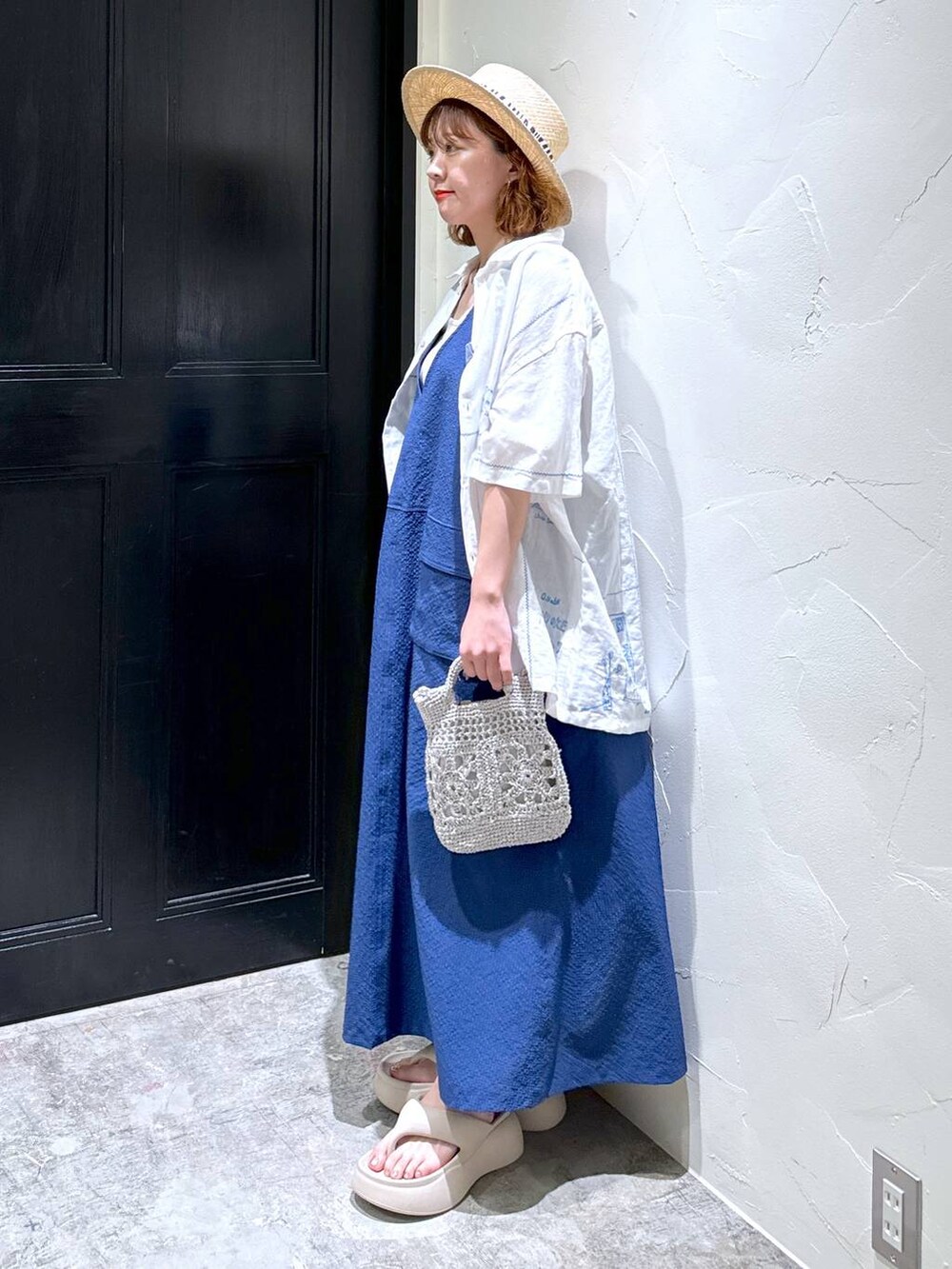 グレー系のショルダーバッグ、ベージュ系のサンダル、ブルー系のジャンパースカートを着用したレディースの夏コーディネートの5枚目の写真