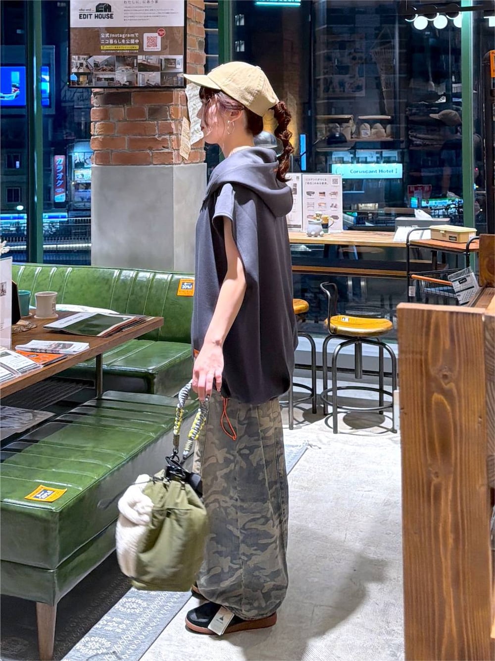 グレー系のベスト、グリーン系のデニムパンツ、グリーン系のショルダーバッグを着用したレディースの夏コーディネートの2枚目の写真