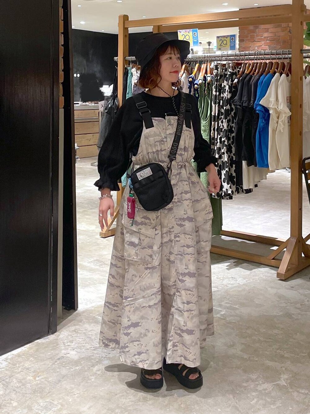 ブラック系のサンダル、ブラック系のTシャツ/カットソー、グリーン系のジャンパースカートを着用したレディースの春コーディネートの2枚目の写真