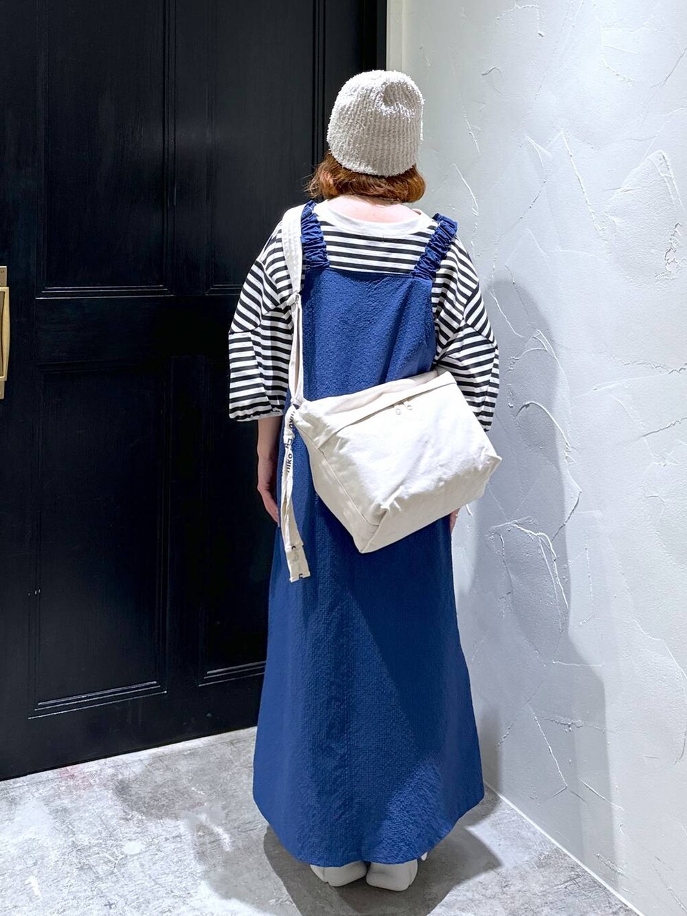 ブルー系のジャンパースカート、ベージュ系のスニーカー、ブラウン系のショルダーバッグを着用したレディースの夏コーディネートの4枚目の写真