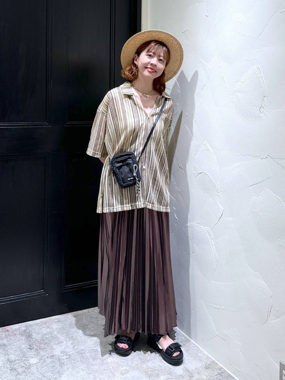 ブラック系のサンダル、ベージュ系のスカート、ブラック系のショルダーバッグを着用したレディースの夏コーディネートの2枚目の写真
