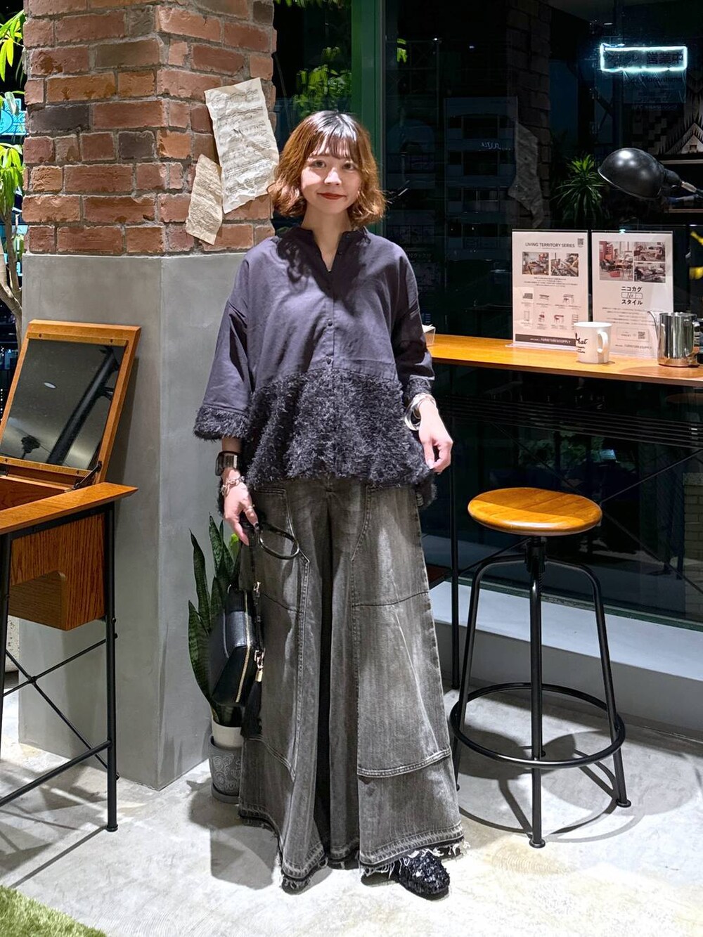 ブラック系のバレエシューズ、ブラック系のショルダーバッグ、ブラウン系のデニムパンツを着用したレディースの秋コーディネートの6枚目の写真