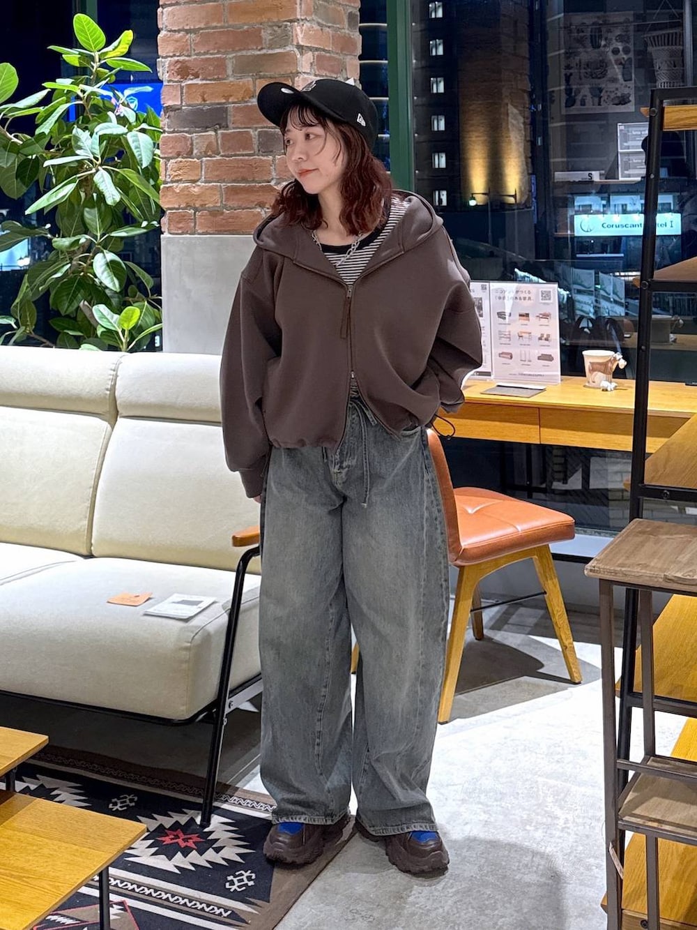 ブラウン系のスニーカー、ブルー系のデニムパンツ、ブラウン系のパーカーを着用したレディースの冬コーディネートの2枚目の写真