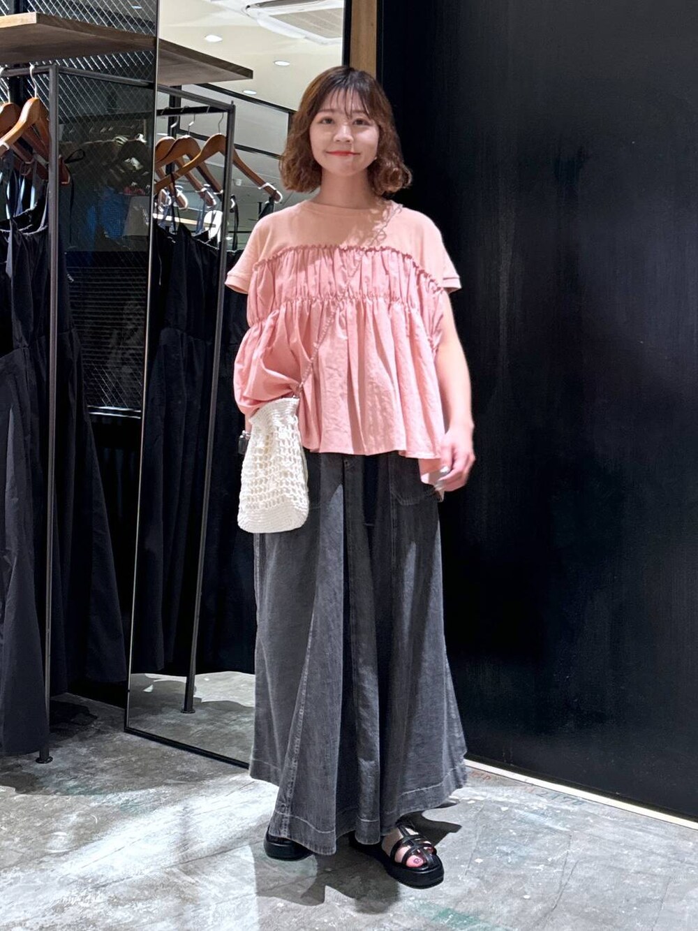 ホワイト系のショルダーバッグ、ブラック系のサンダル、グレー系のスカートを着用したレディースの夏コーディネートの2枚目の写真