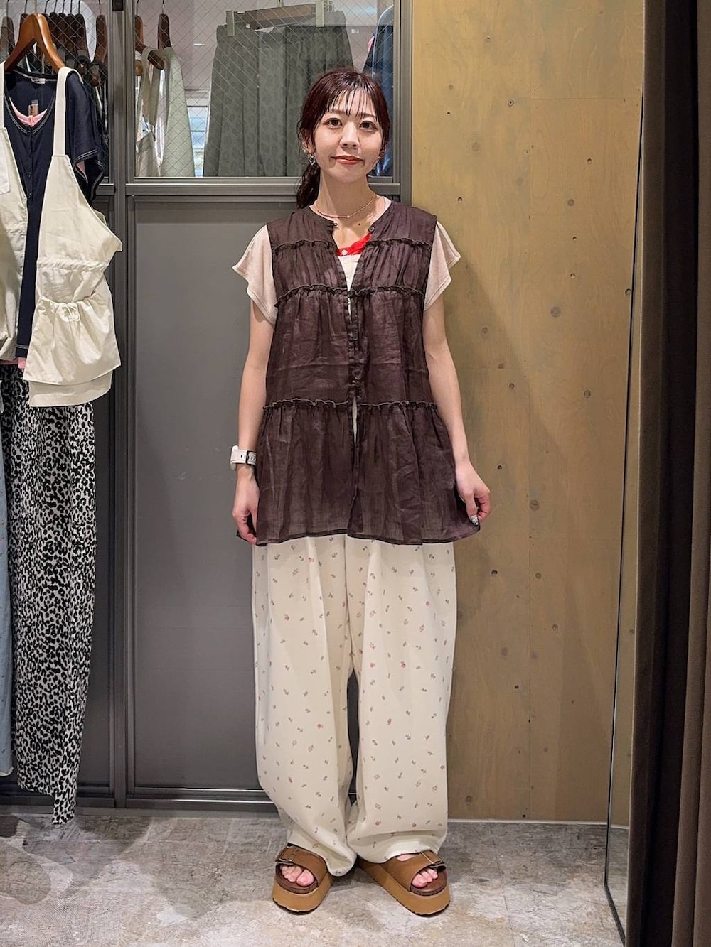 ブラウン系のベスト、ブラウン系のサンダル、ベージュ系のTシャツ/カットソーを着用したレディースの夏コーディネートの2枚目の写真
