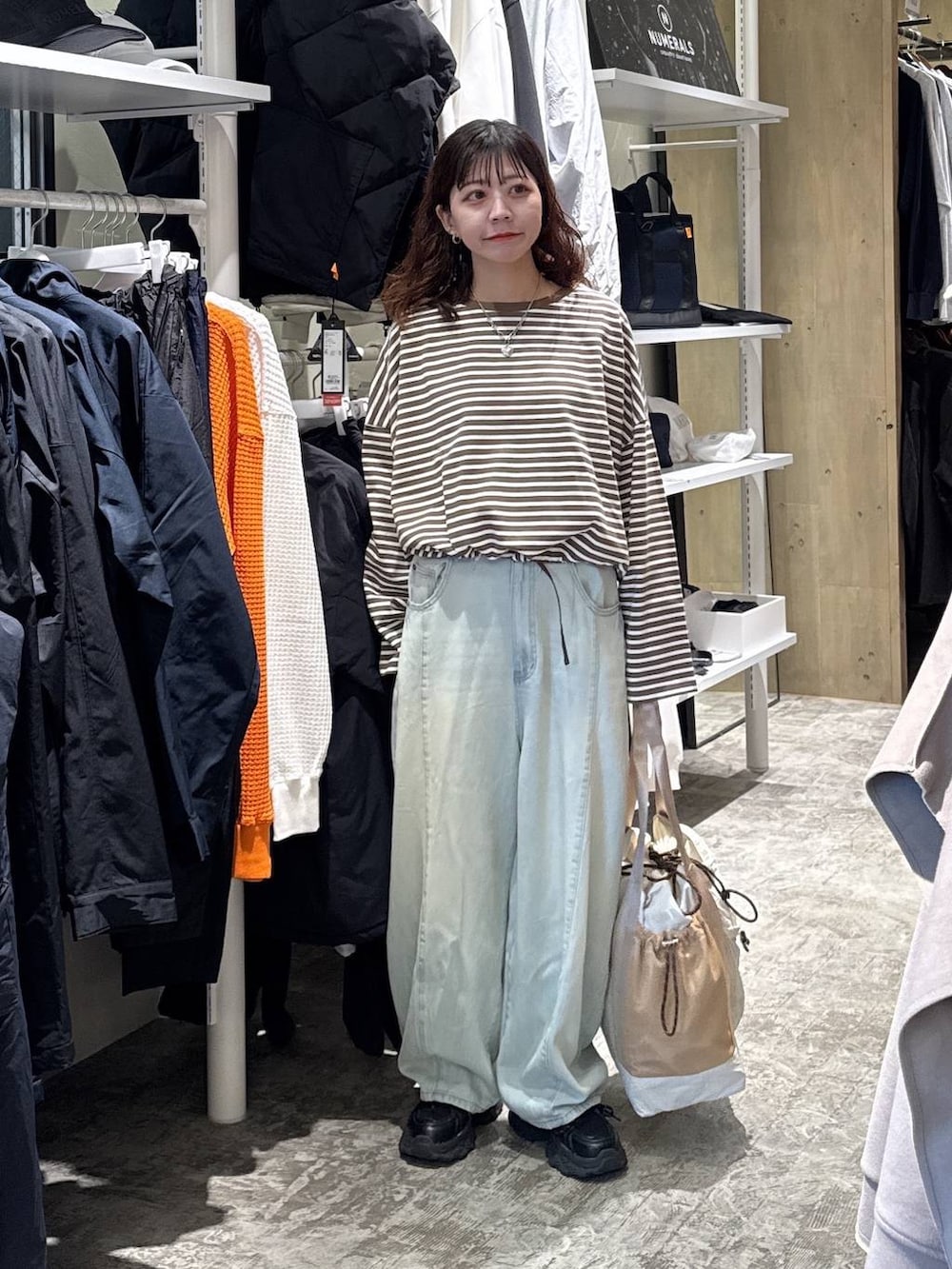 ブラック系のスニーカー、グリーン系のデニムパンツ、ベージュ系のトートバッグを着用したレディースの冬コーディネートの6枚目の写真