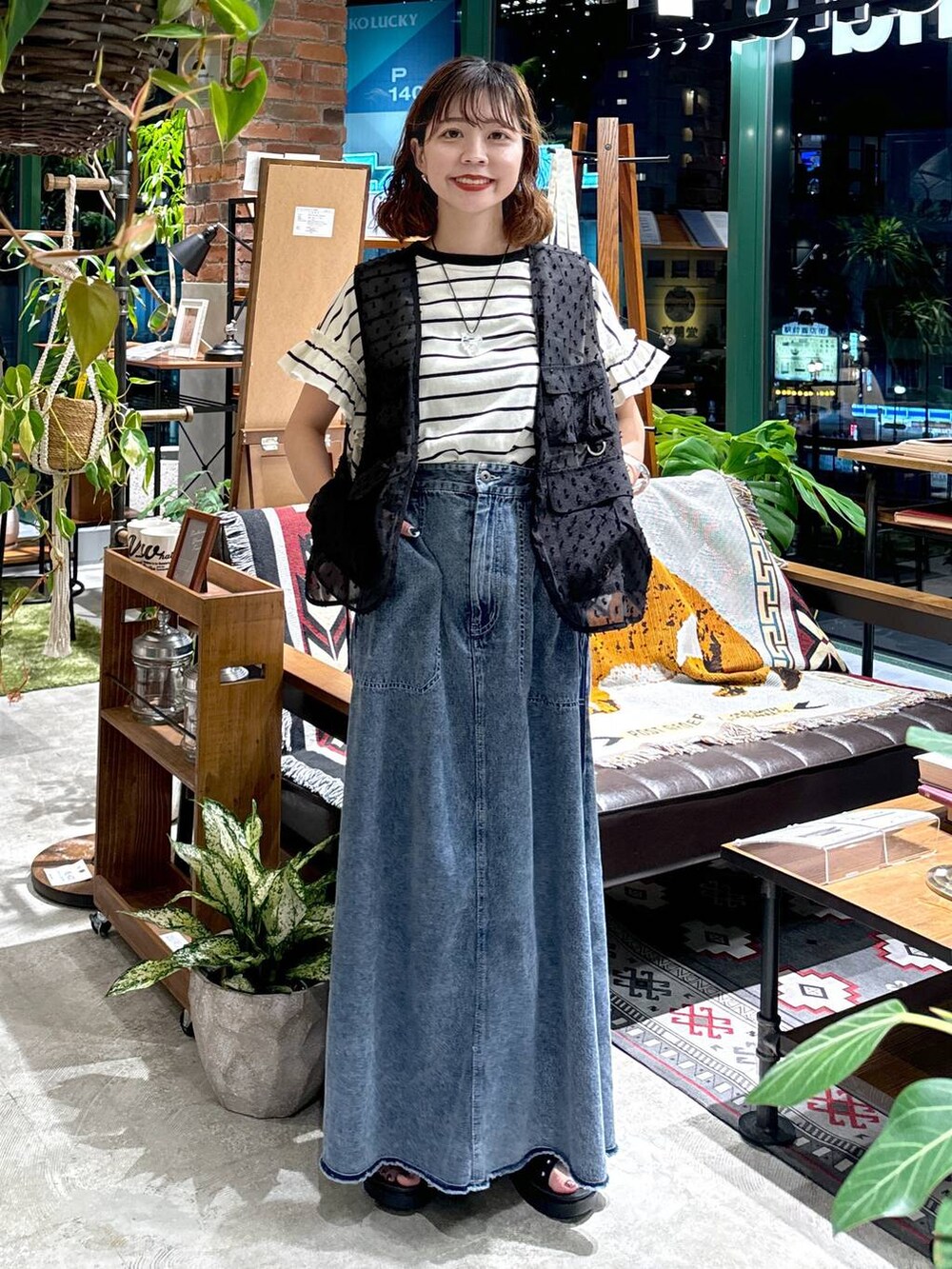 ブラック系のサンダル、ブラック系のベスト、ブルー系のスカートを着用したレディースの夏コーディネートの3枚目の写真