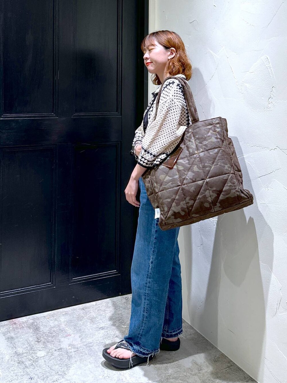 ブラック系のTシャツ/カットソー、ブラック系のサンダル、ブルー系のデニムパンツを着用したレディースの夏コーディネートの4枚目の写真