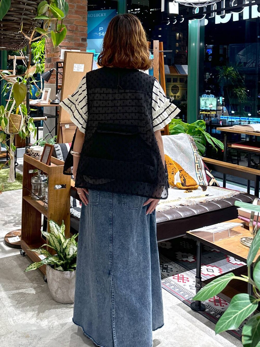 ブラック系のサンダル、ブラック系のベスト、ブルー系のスカートを着用したレディースの夏コーディネートの6枚目の写真